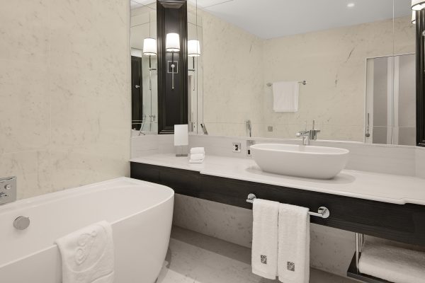 Marble bathroom at Fairmont Windsor Park with freestanding tub, vessel sink, and monogrammed towels.