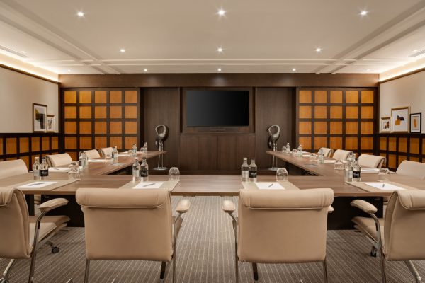 The Lilac meeting room at Fairmont Windsor Park with a large conference table, leather chairs and modern presentation screen.