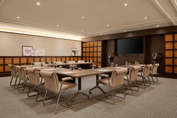 Stylish and modern meeting room at Fairmont Windsor Park with long conference table, beige chairs, and modern decor.