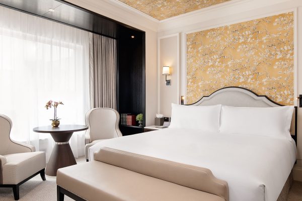 King room at Fairmont Windsor Park with a king-sized bed, floral wallpaper, and a cosy seating area by a large window.