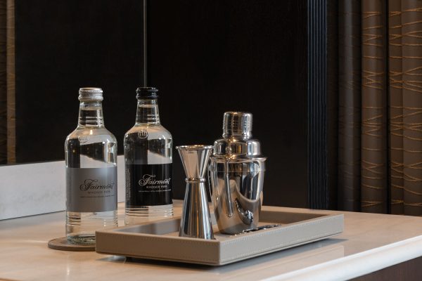Premium minibar setup at Fairmont Windsor Park featuring bottled water, a cocktail shaker, and a jigger on a stylish tray.