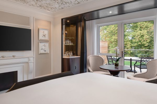 Elegant guest room at Fairmont Windsor Park with garden view, beige armchairs, and modern décor.