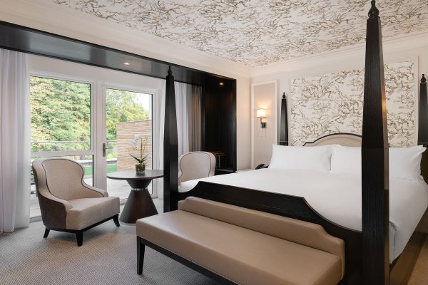 Elegant Deluxe King Room at Fairmont Windsor Park with a four-poster bed, seating area, and private terrace with garden view.
