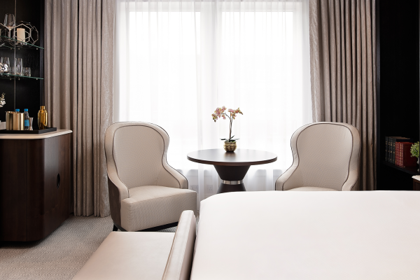 Luxurious room at Fairmont Windsor Park with minibar, plush armchairs, and soft-lit ambiance creating warmth.