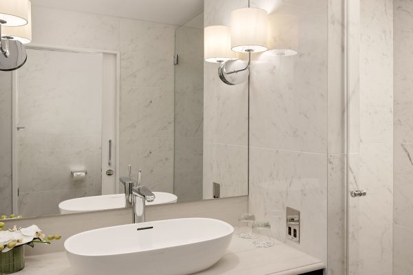 Stylish marble bathroom at Fairmont Windsor Park with modern white sink, warm lighting, and orchid decor.