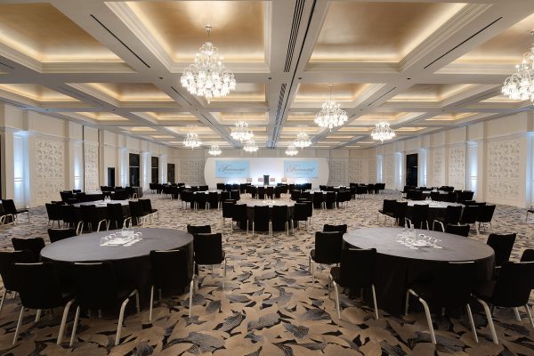 Arora Ballroom at Fairmont Windsor Park set up for a corporate event with round tables and chandeliers.