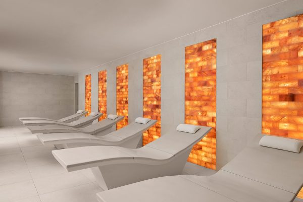 Relaxing spa room at Fairmont Windsor Park with heated loungers and illuminated Himalayan salt walls.