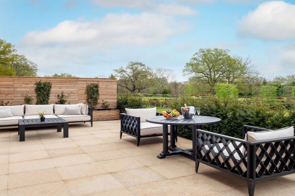 Outdoor terrace at Fairmont Windsor Park with plush seating, dining table, and views of manicured gardens.
