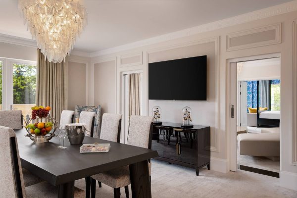 Sophisticated dining room at the Royal Suite at Fairmont Windsor Park with black table, large chandelier and adjoining suite.