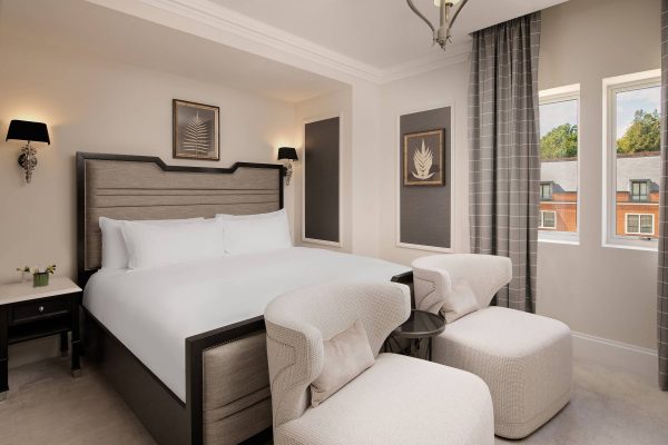 Luxury two bedroom suite at Fairmont Windsor Park with a king-sized bed, and large windows overlooking the grounds.