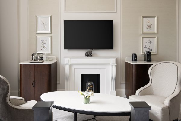 Refined hotel lounge at Fairmont Windsor Park with cosy fireplace, plush seating, framed artwork, and modern TV.