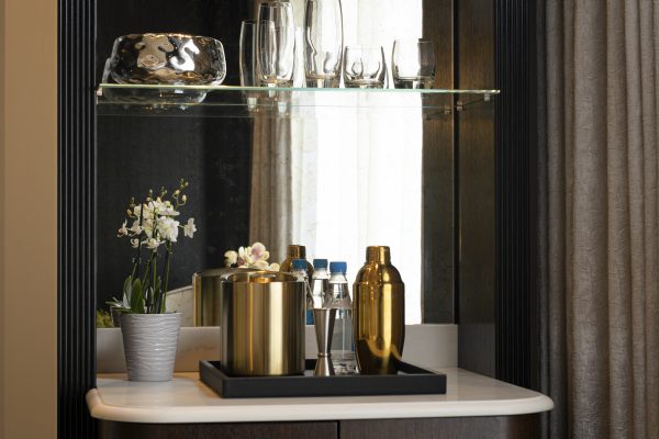 Luxury minibar at Fairmont Windsor Park with gold cocktail shaker, ice bucket, and premium bottled water in a stylish alcove.