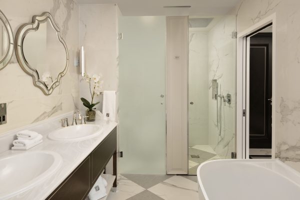 Luxurious bathroom at Fairmont Windsor Park with double vanity, elegant mirrors, and spacious glass shower.
