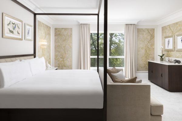 Spacious Royal Suite with four-poster king bed, bird artwork, and large window showcasing lush greenery.