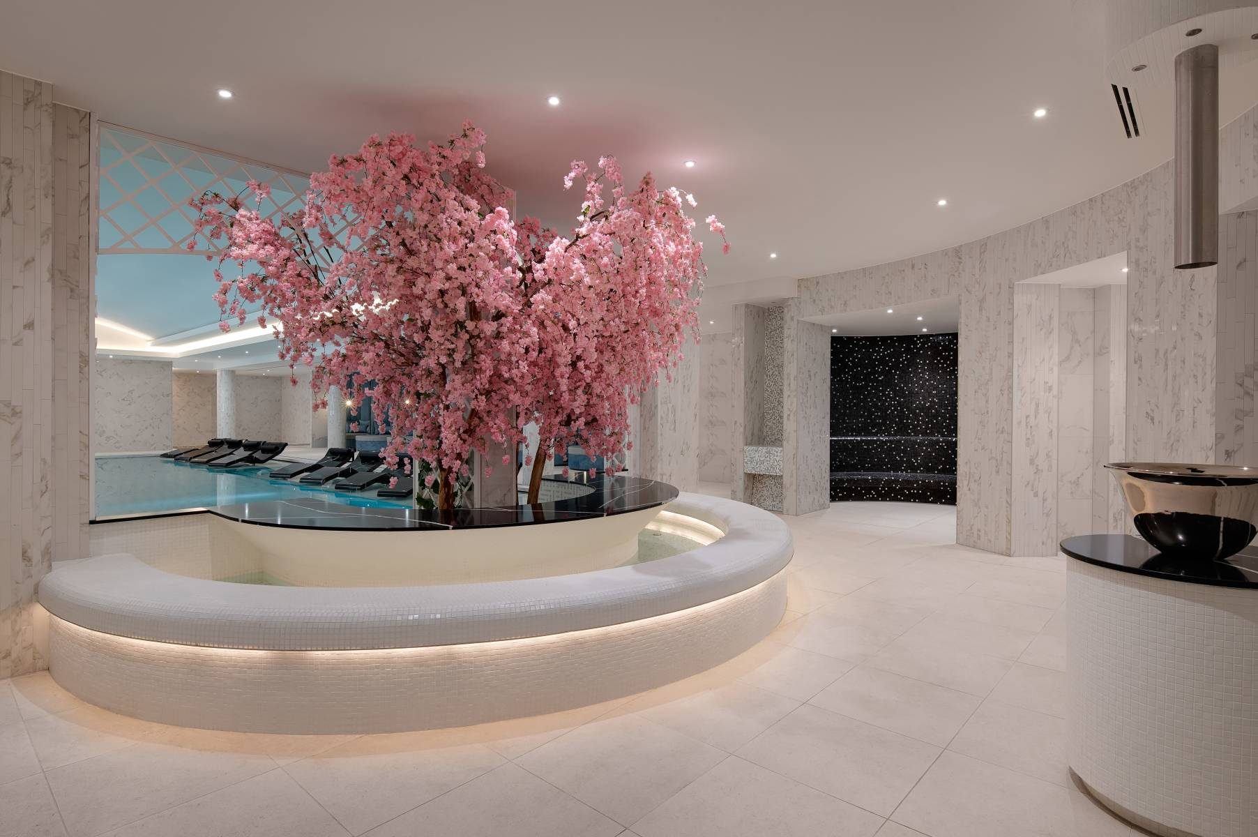 Tranquil spa entrance at Fairmont Windsor Park with cherry blossom tree centrepiece and elegant marble surroundings.