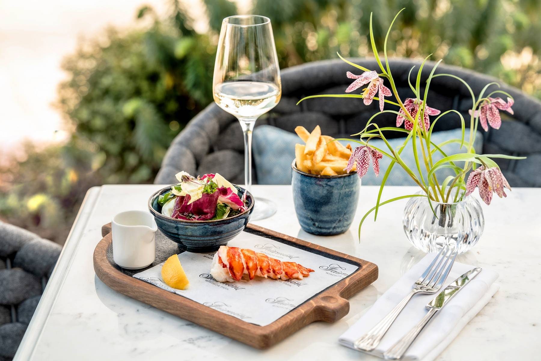 Outdoor dining with fresh lobster, salad, crispy fries, and a glass of white wine in The Terrace at Fairmont Windsor Park.