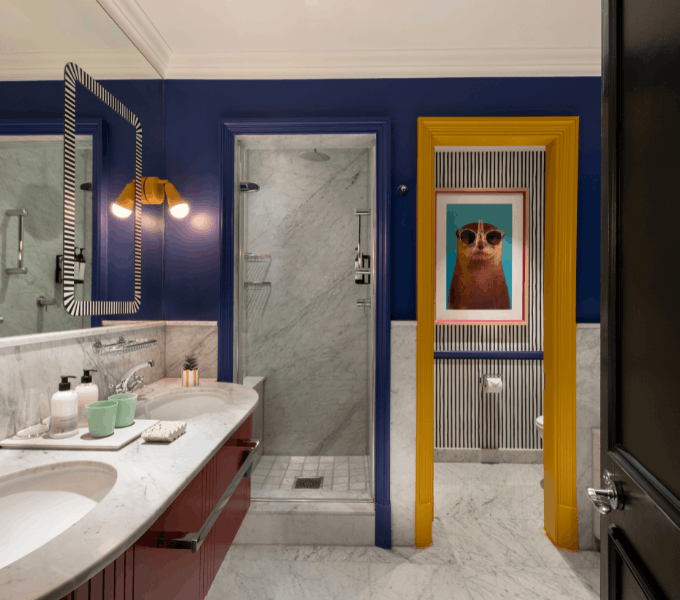 Elegant family suite bathroom at Cape Grace with marble finishes, colourful accents, and a walk-in shower.