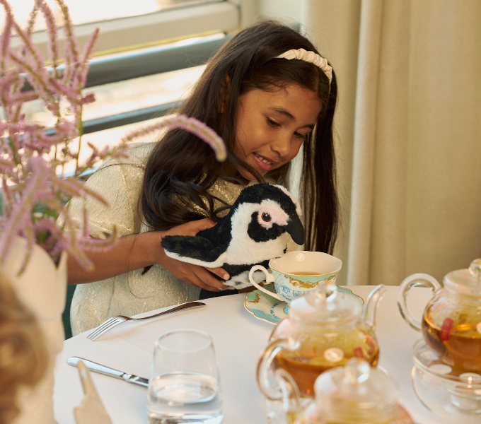 Young girl enjoying a Kiddies Afternoon Tea experience at Cape Grace with a plush toy and elegant teacup setting.