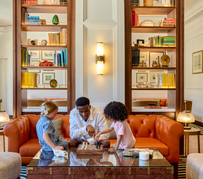 Family enjoying a game together in the elegant Cape Grace Library Lounge, surrounded by warm interiors and curated bookshelves.