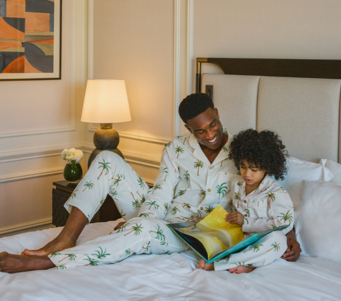 Parent and child reading together on a bed at Cape Grace, highlighting a warm and intimate family stay experience.