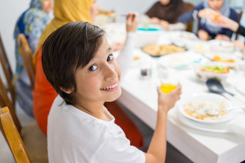 Family gathering eating meal around kitchen table